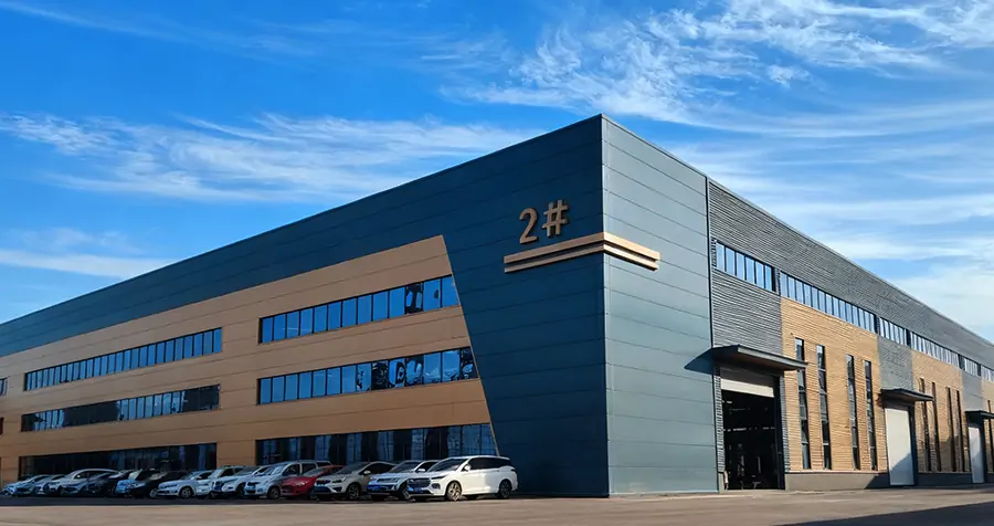 About Us 2 Wide-angle photograph of XQ Machinery's #2 modern manufacturing base, featuring an XQ-YC100 10-ton 4WD forklift and other XQ series models in the foreground. The view shows a spotless industrial campus and workshop access.